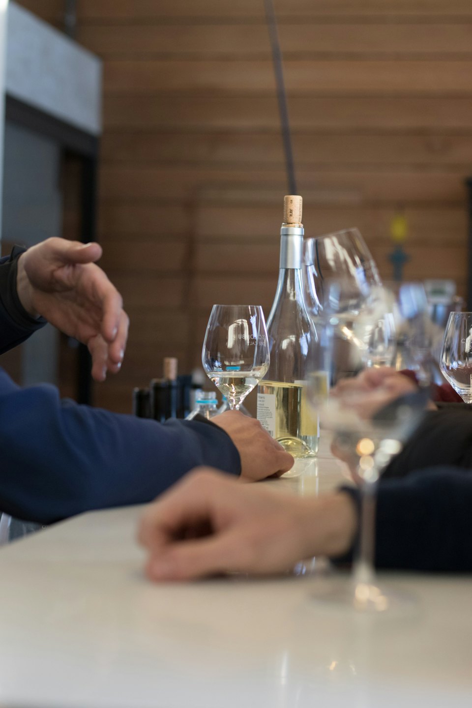 Gente probando vino blanco en una barra.