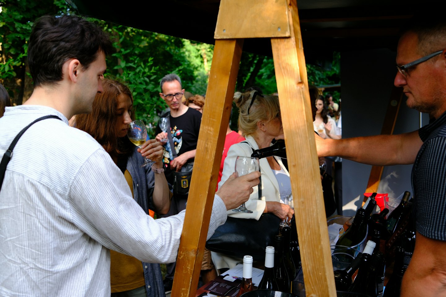 Gente disfrutando de una degustación de vinos en un puesto rústico al aire libre.