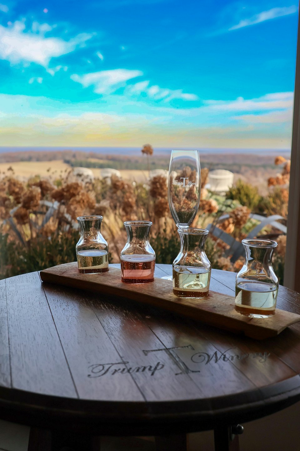 Copa de vino de degustación sobre una mesa de barril con vistas a colinas onduladas.